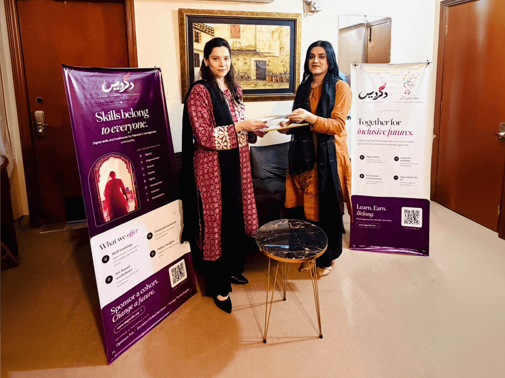 Two women exchanging documents beside Degardis banners at a partnership meeting