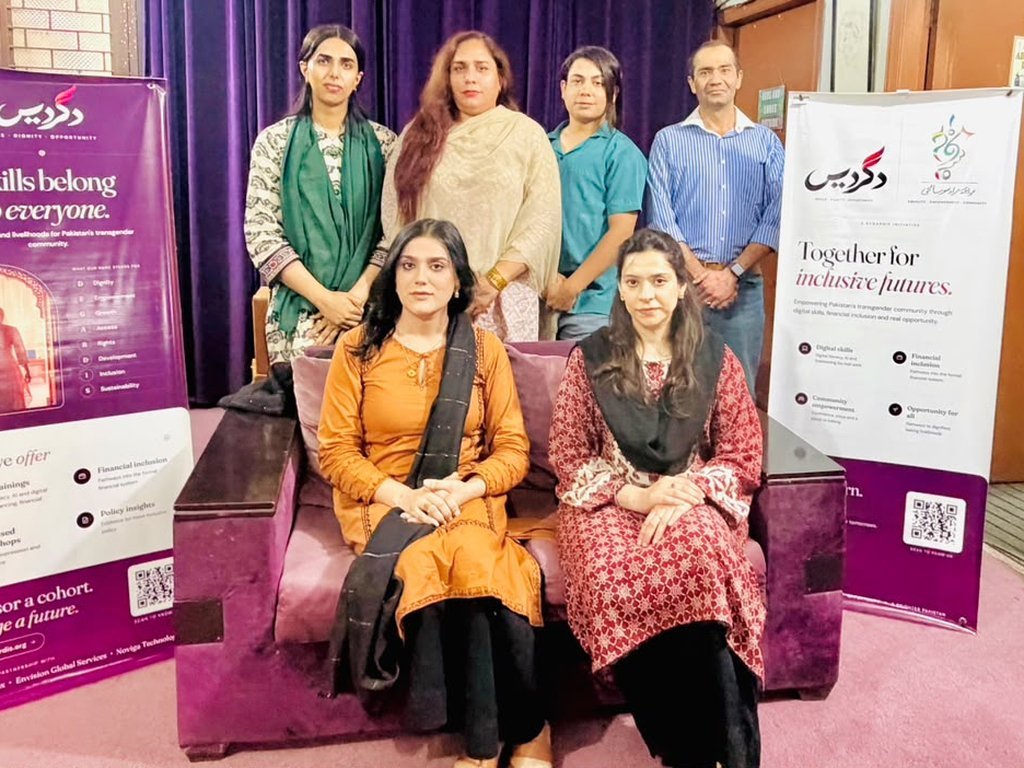 Degardis team members seated and standing between Degardis banners in Lahore